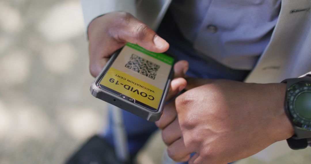 Man Holding Smartphone with COVID-19 Vaccine Pass and Smartwatch
