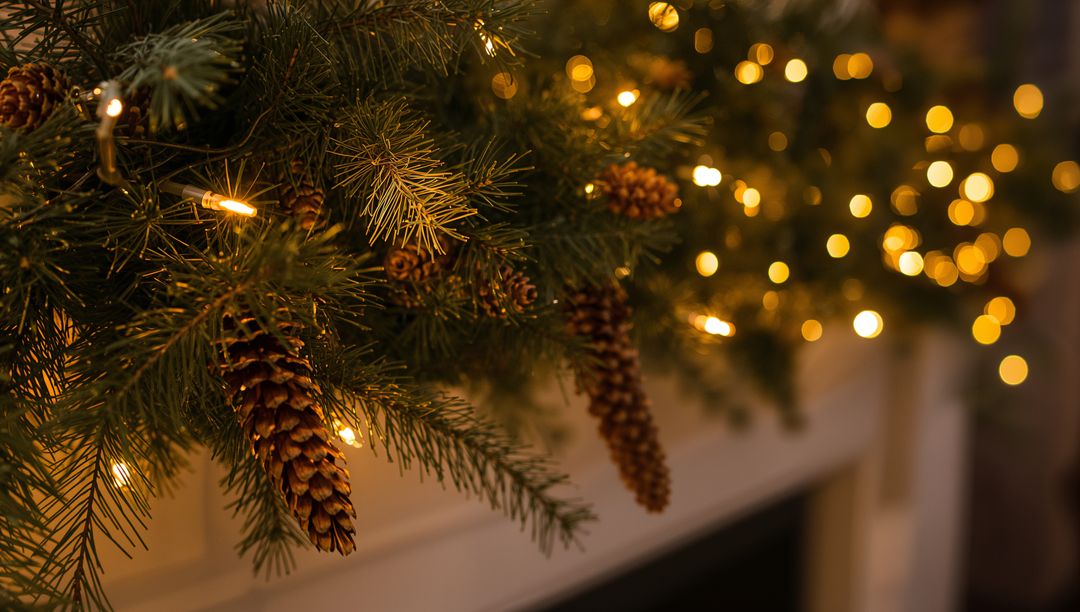Evergreen Mantel Garland Draping with Pinecones and Warm Bokeh Lights
