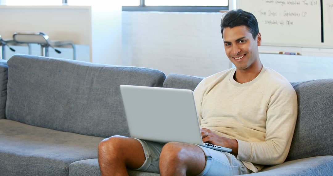 Young Man Relaxing on Sofa with Laptop Working from Home - Free Images, Stock Photos and Pictures on Pikwizard.com