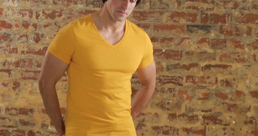 Casual Man in Yellow T-Shirt Against Brick Wall Background - Free Images, Stock Photos and Pictures on Pikwizard.com