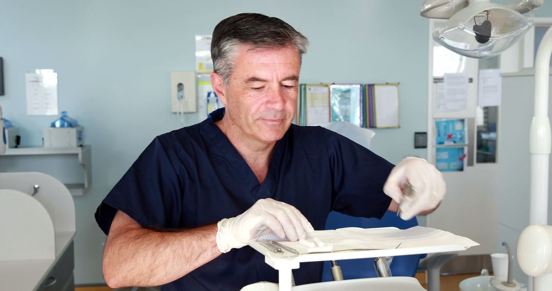 Elderly male dentist preparing for dental procedure in clinic - Free Images, Stock Photos and Pictures on Pikwizard.com