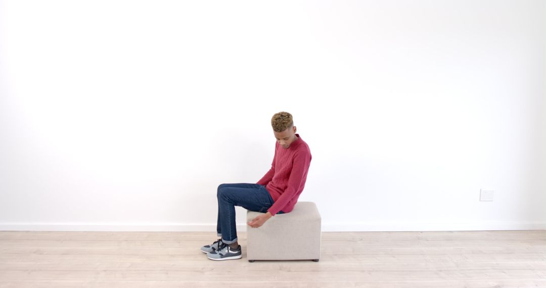 Young Man Practicing Seated Exercises on Ottoman in Minimalist Space