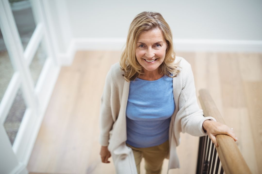 Smiling senior woman climbing upstairs at home - Free Images, Stock Photos and Pictures on Pikwizard.com