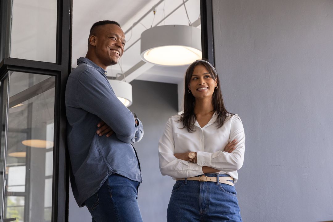 Diverse coworkers collaborating confidently in modern office corridor under pendant lights