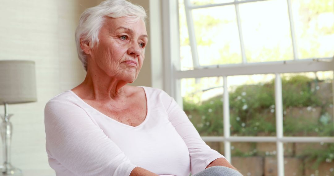 Pensive Senior Woman Sitting by Window - Free Images, Stock Photos and Pictures on Pikwizard.com