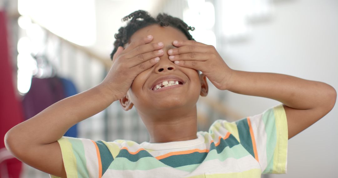 Playful Child Covering Eyes While Smiling at Home