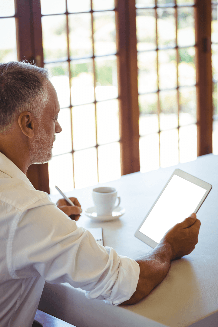 Mature Man Sitting in Cafe with Transparent Tablet Screen