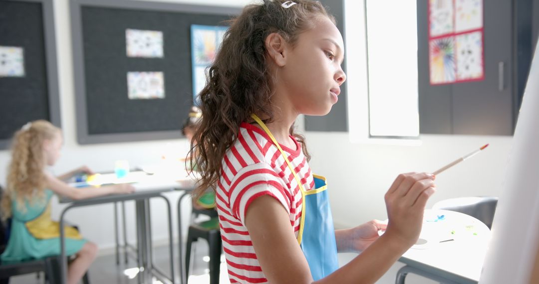 Young Girl Concentrating on Painting in Creative Classroom