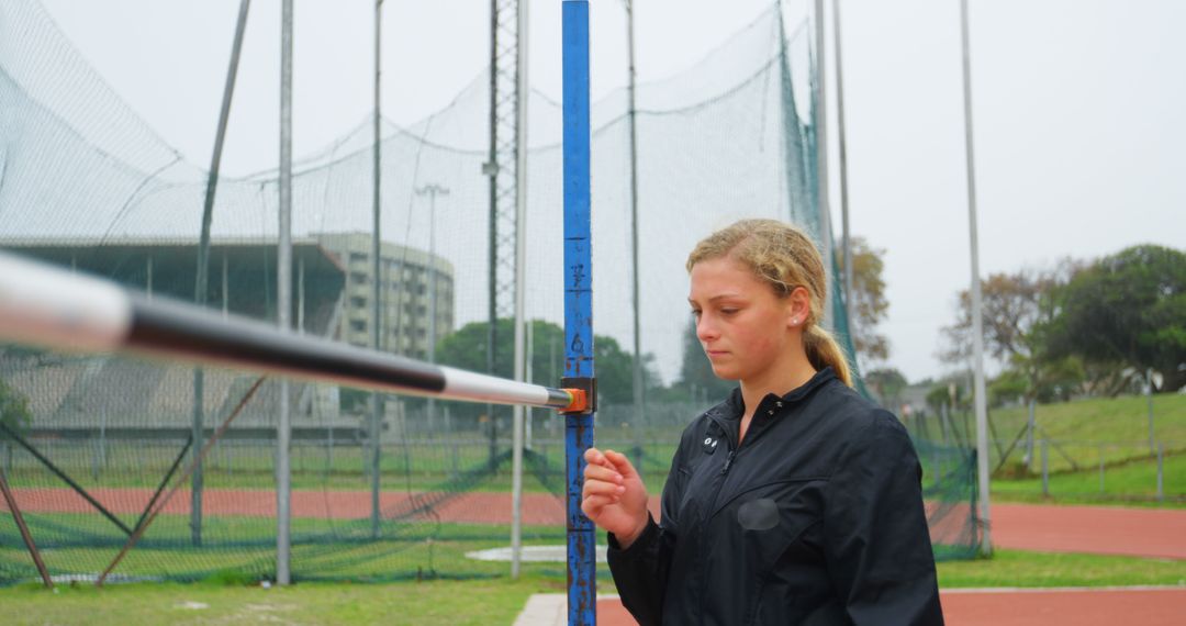 Female Athlete Adjusting High Jump Bar on Outdoor Track Field - Free Images, Stock Photos and Pictures on Pikwizard.com