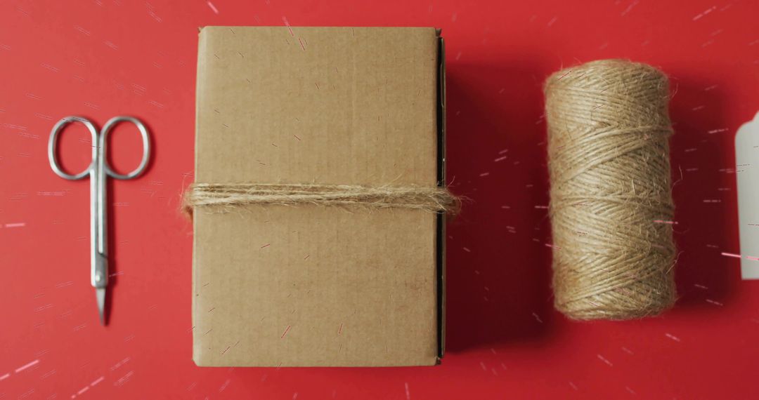 Crafting rustic gift box wrapped with jute twine on red flatlay for handmade packaging