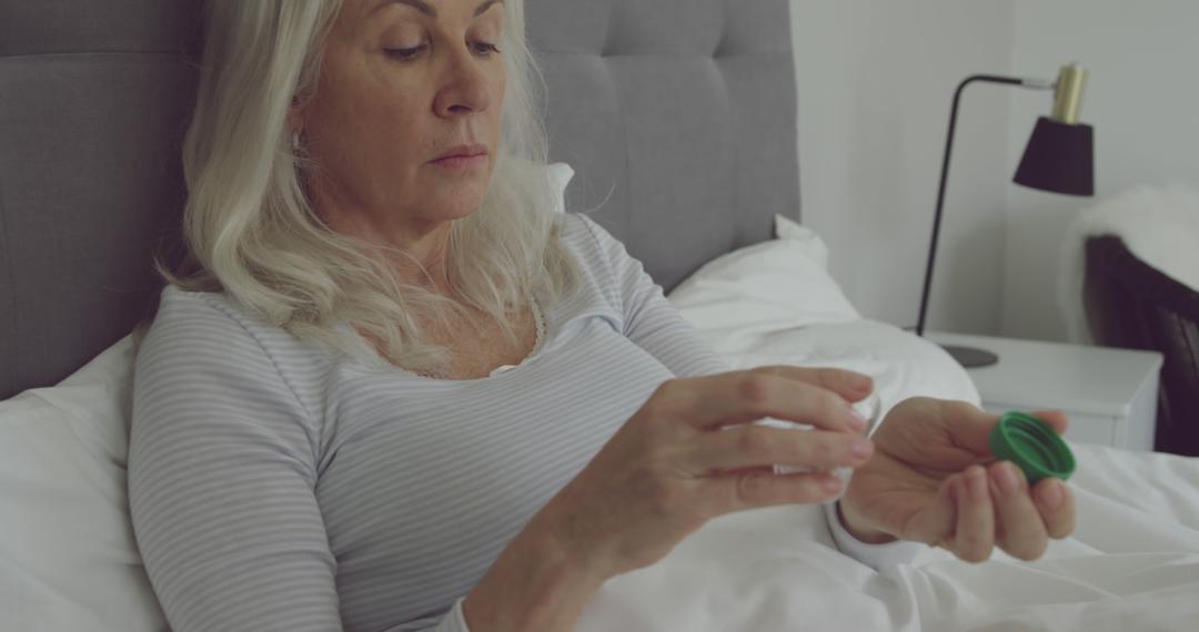 Elderly Woman Taking Medication in Bed in Cozy Room - Free Images, Stock Photos and Pictures on Pikwizard.com