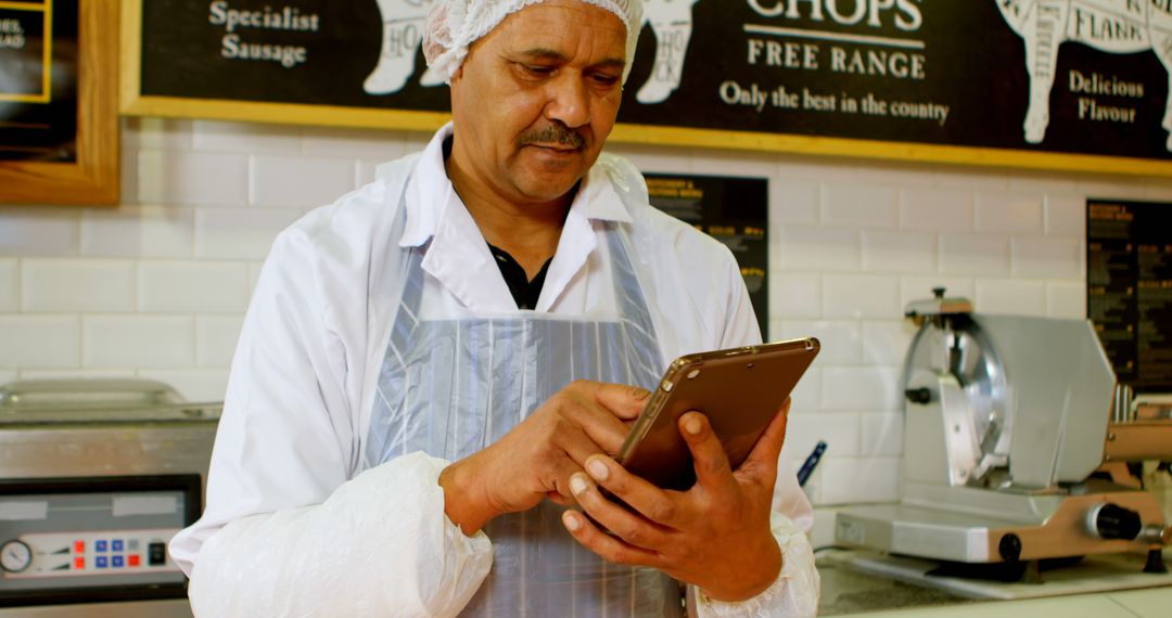 Butcher in apron using digital tablet in butcher shop - Free Images, Stock Photos and Pictures on Pikwizard.com