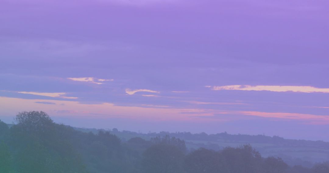 Pastel Dawn Over Misty Countryside: Rolling Hills, Tree Silhouettes and Soft Twilight Haze