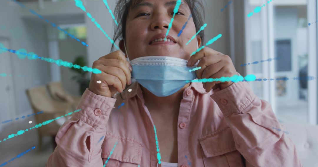 Pulling surgical mask beneath chin smiling Korean man removing mask in sunlit lobby