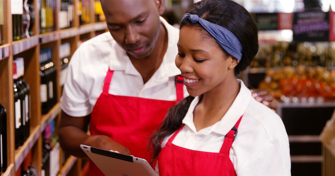 Supermarket Employees in Red Aprons Using Digital Tablet - Free Images, Stock Photos and Pictures on Pikwizard.com