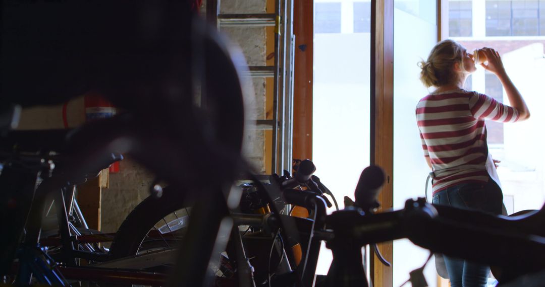 Woman Drinking Water in Workshop with Bicycles - Free Images, Stock Photos and Pictures on Pikwizard.com