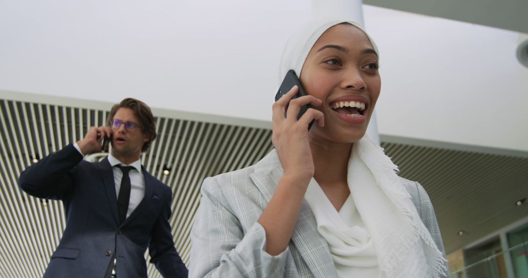 Smiling Businesswoman Talking on Phone While Colleague in Background - Free Images, Stock Photos and Pictures on Pikwizard.com