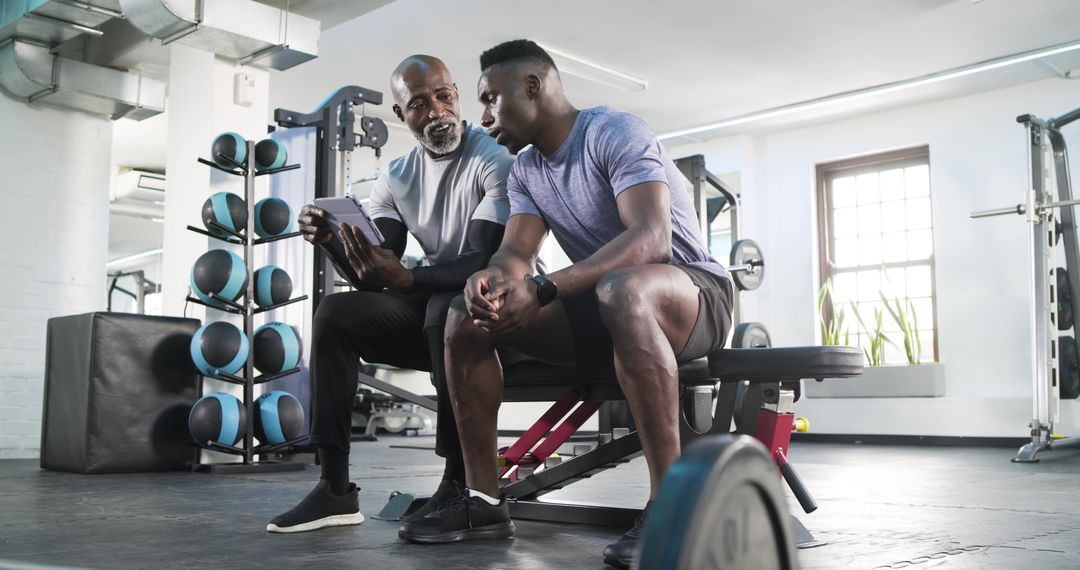Fitness Trainer Guiding Client with Tablet in Gym