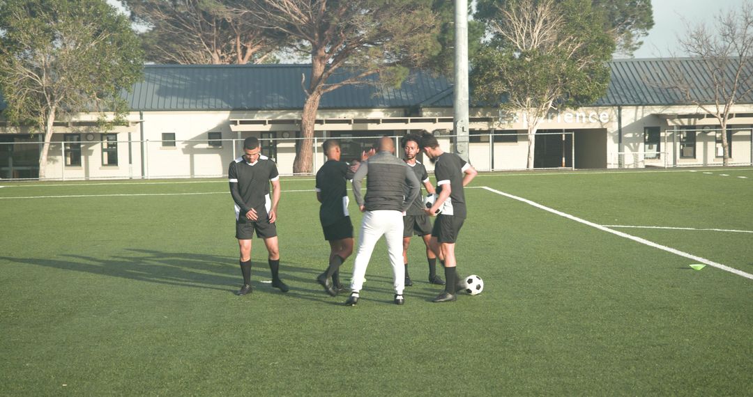 Soccer Players Practice Dribbling Techniques with Coach on Field