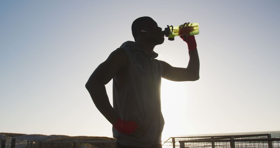 Athletic man hydrating after outdoor workout at sunrise - Free Images, Stock Photos and Pictures on Pikwizard.com