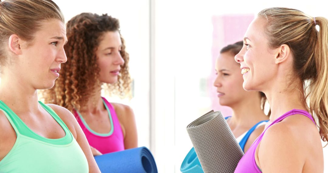 Women Conversing Holding Yoga Mats in Fitness Studio - Free Images, Stock Photos and Pictures on Pikwizard.com