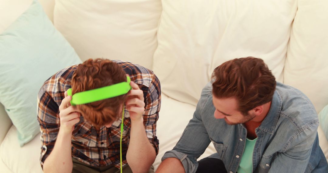 Two Young Men Relaxing with Headphones on Comfortable Couch - Free Images, Stock Photos and Pictures on Pikwizard.com