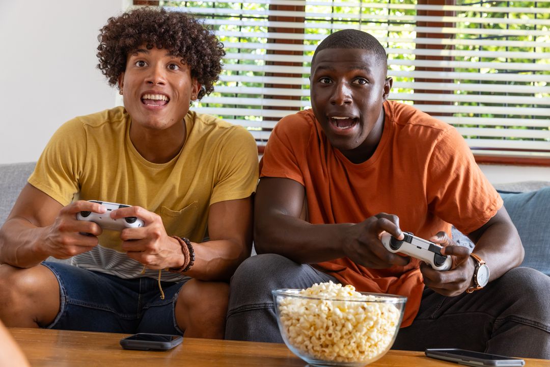Friends Enthusiastically Gaming with Snacks and Consoles