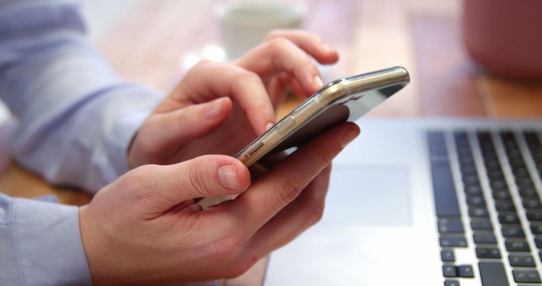 Person Multitasking with Smartphone and Laptop in Office Setting