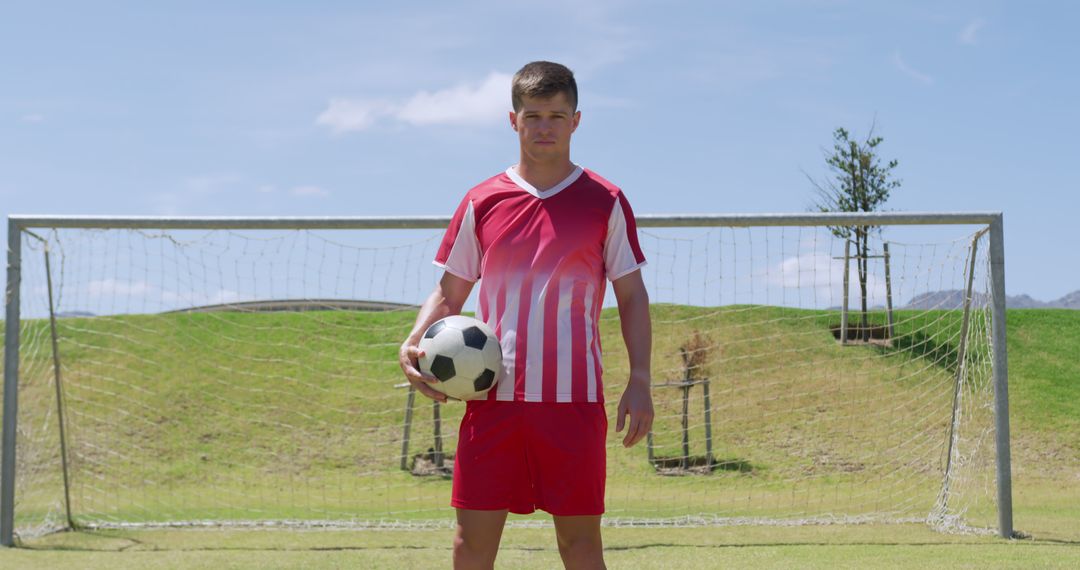 Confident Soccer Player Holding Ball on Field by Goalpost - Free Images, Stock Photos and Pictures on Pikwizard.com