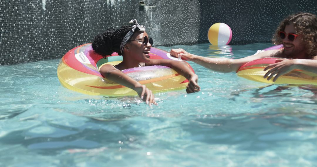 Diverse Couple Joyfully Relaxing in Pool with Colorful Floats