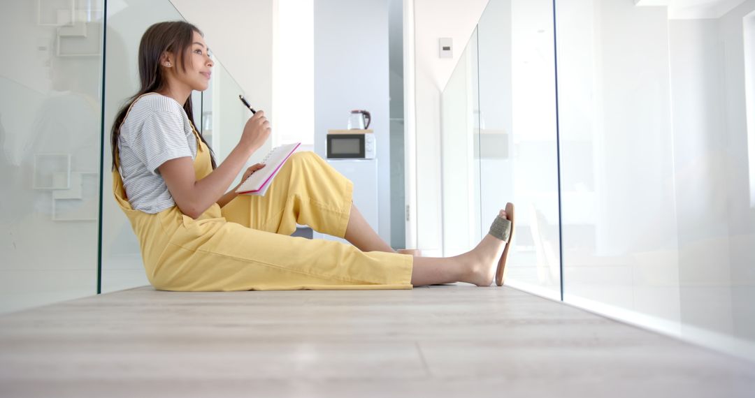 Woman Contemplating While Writing Notebook in Modern Home Environment