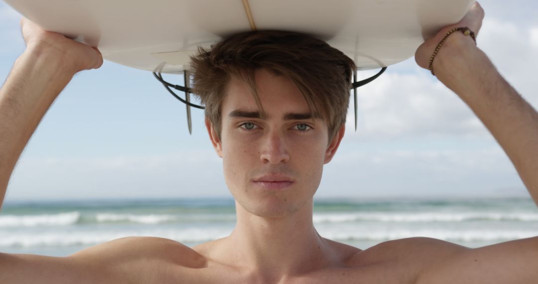 Young Male Surfer Holding Surfboard Overhead on Beach - Free Images, Stock Photos and Pictures on Pikwizard.com