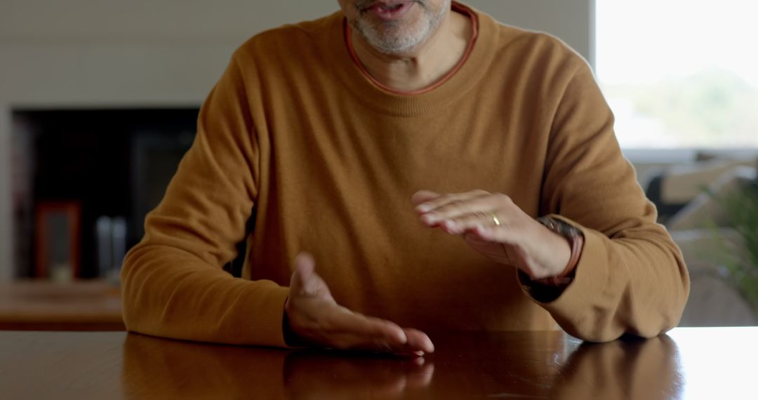 Senior Man Gesturing While Talking at Home Table