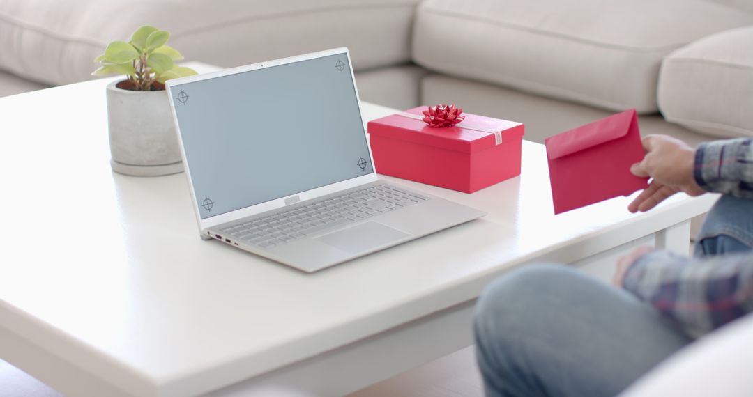 Person Holding Red Envelope Sitting by Laptop with Red Gift Box - Free Images, Stock Photos and Pictures on Pikwizard.com