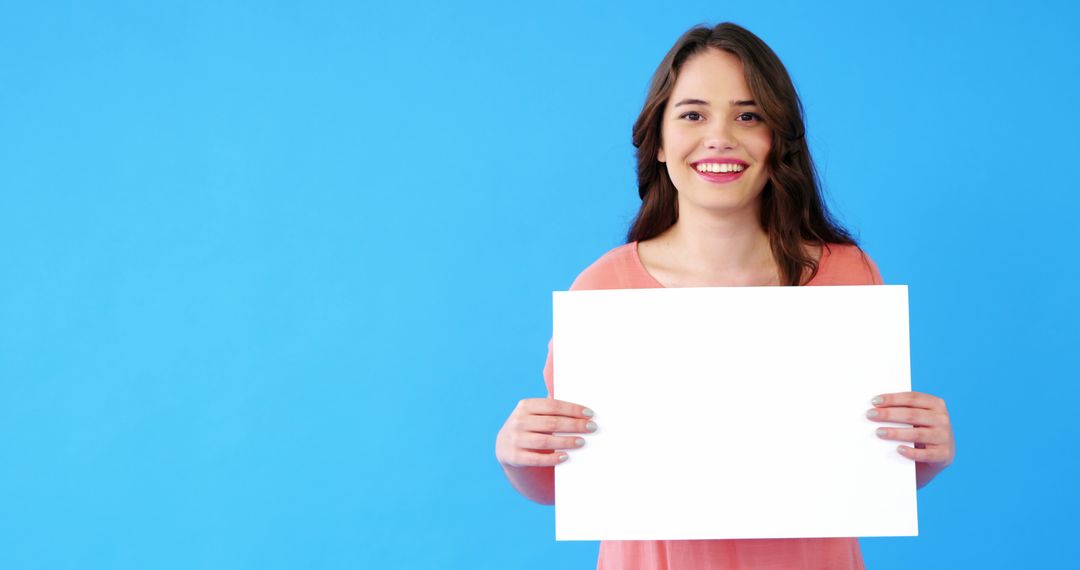 Smiling Woman Holding Blank Sign Against Blue Background - Free Images, Stock Photos and Pictures on Pikwizard.com