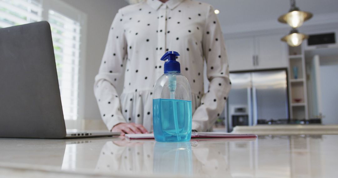 Woman in Polka Dotted Shirt Using Hand Sanitizer at Work Desk - Free Images, Stock Photos and Pictures on Pikwizard.com