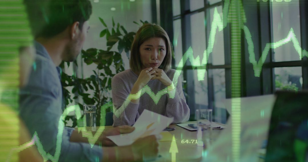 Colleagues Discussing Financial Data Amidst Graph Overlay
