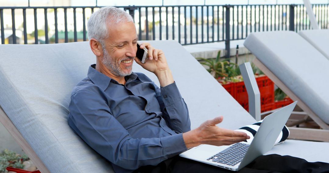 Mature Businessman Enjoying Outdoor Work on Laptop While Talking on Phone - Free Images, Stock Photos and Pictures on Pikwizard.com