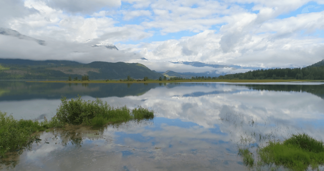 Scenic Transparent Lake Reflection of Clouds and Mountains