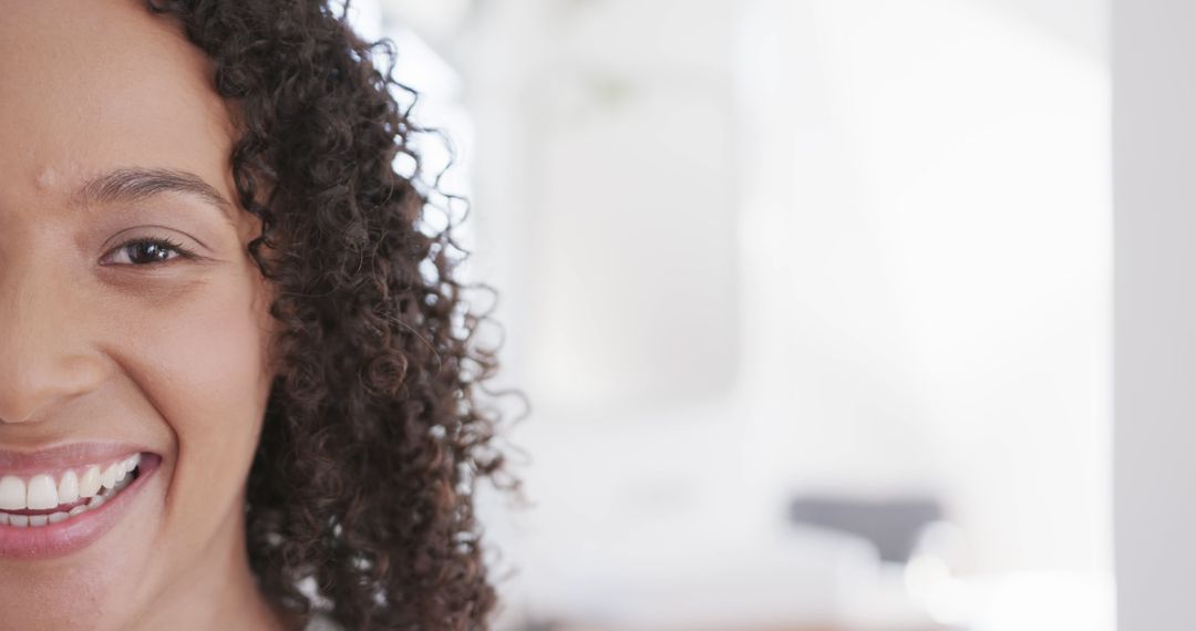 Half Face of Smiling Woman with Curly Hair in Soft Light