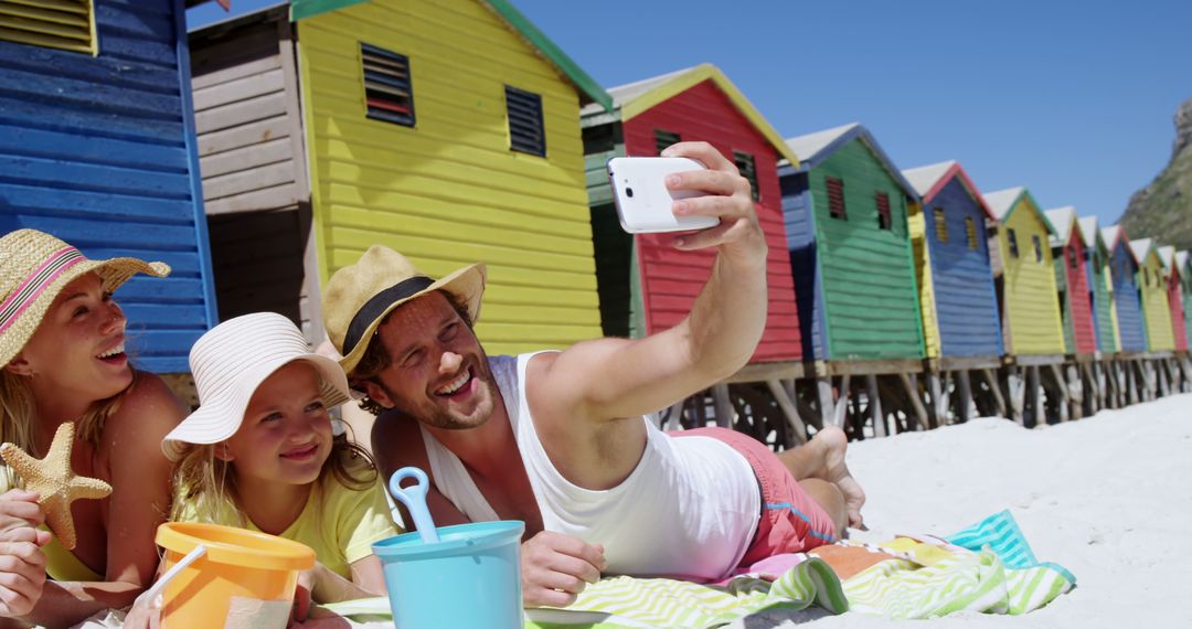 Family Taking Selfie on Beach Near Colorful Beach Huts - Free Images, Stock Photos and Pictures on Pikwizard.com