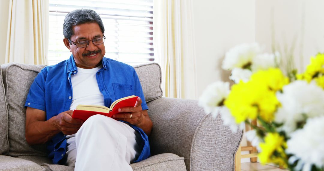 Senior Man Reading Book on Comfortable Sofa in Living Room - Free Images, Stock Photos and Pictures on Pikwizard.com