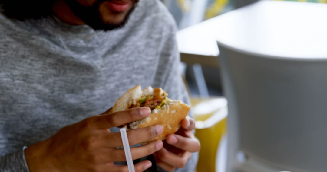 Man Eating Burger in Casual Setting with Focus on Meal - Free Images, Stock Photos and Pictures on Pikwizard.com