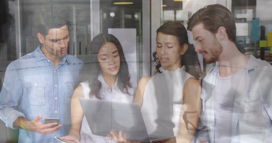 Diverse Team Engaged in Office Collaboration Using Laptop and Smartphone