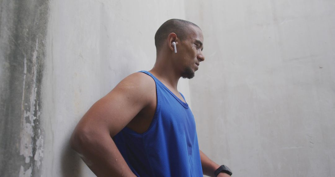 Sweaty biracial sports man wearing blue tshirt and earphones in city - Free Images, Stock Photos and Pictures on Pikwizard.com