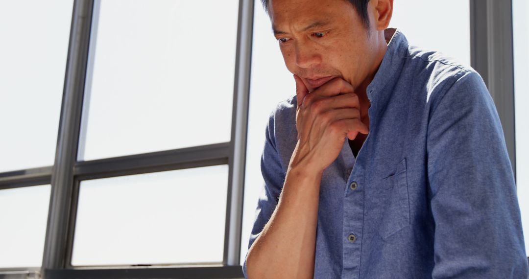 Focused Asian Architect Analyzing Project Plans in Modern Office