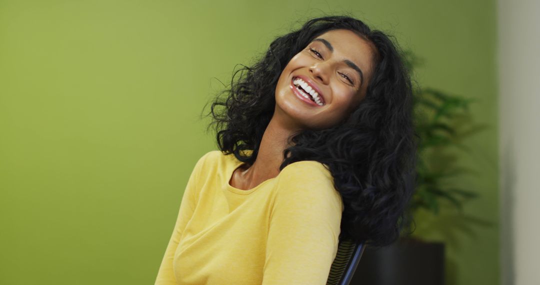 Image of happy biracial woman looking at camera on green background - Free Images, Stock Photos and Pictures on Pikwizard.com