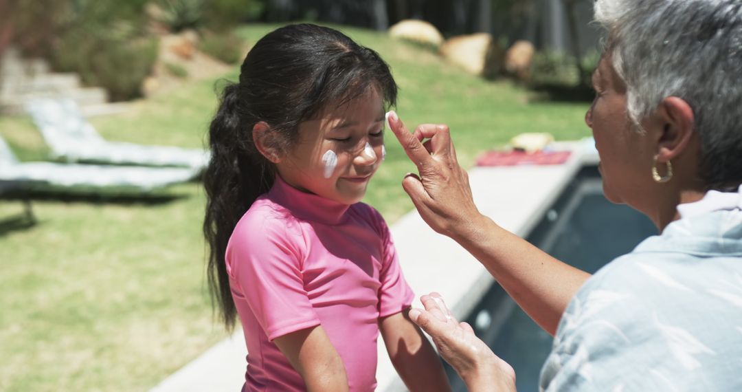 Grandparent Applying Sunscreen to Granddaughter by Poolside