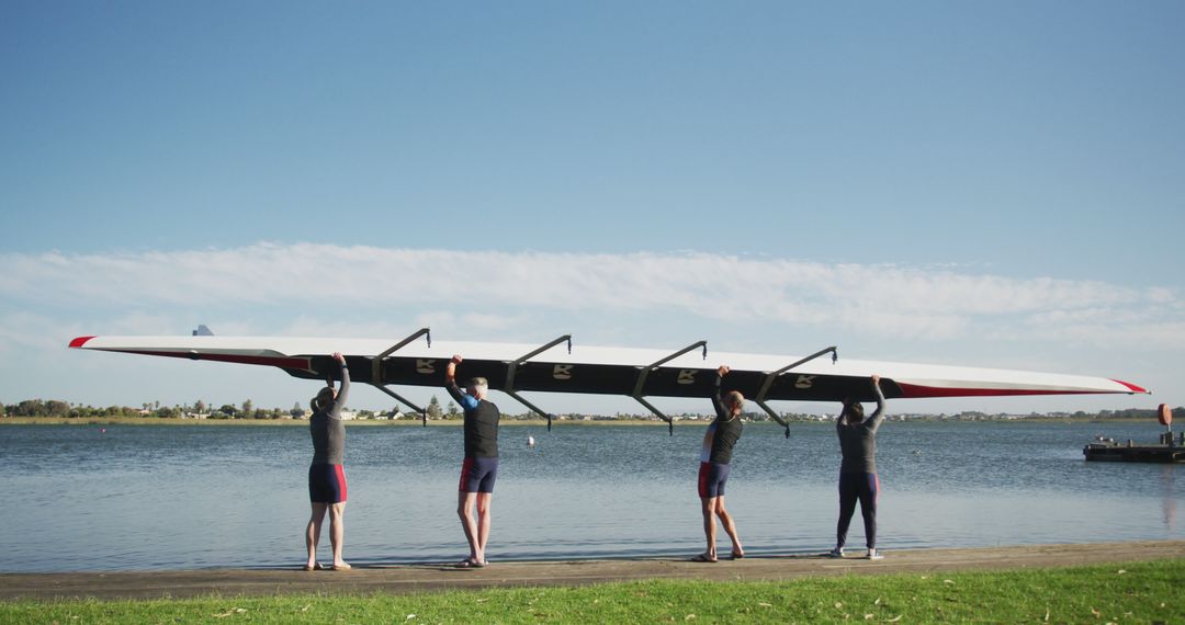 Rowing Team Lifting Boat Near River Shore Under Sunny Sky - Free Images, Stock Photos and Pictures on Pikwizard.com