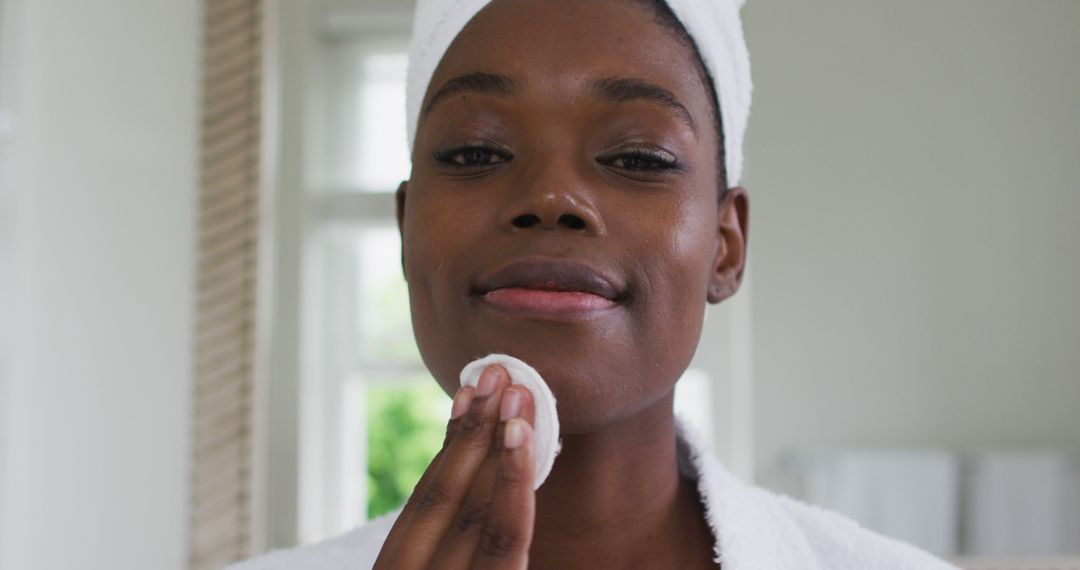 African American woman practices skincare with a cotton pad during quarantine at home. - Free Images, Stock Photos and Pictures on Pikwizard.com